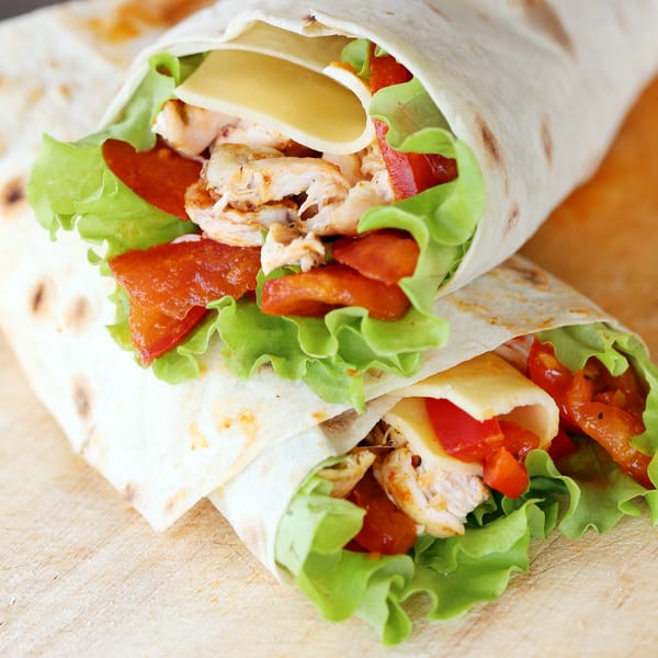 Two El Molino chicken wraps with lettuce, cheese, and red peppers on a wooden surface.