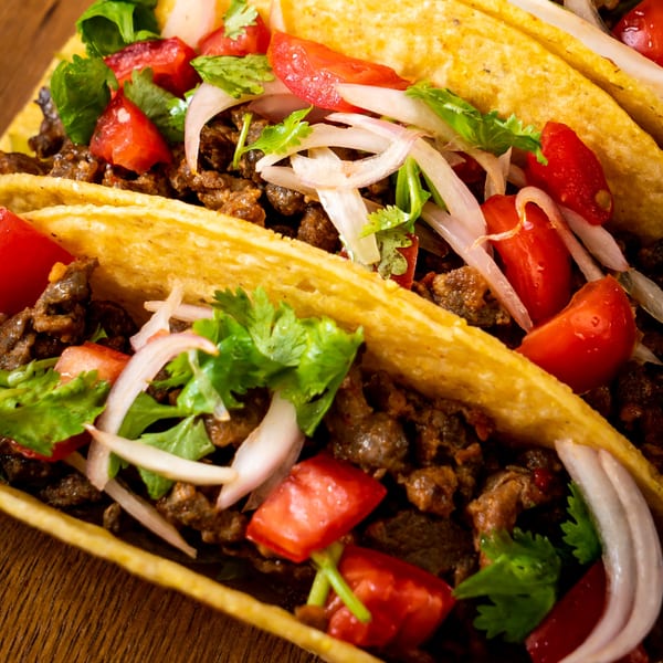 Close-up of El Molino's Mexican tacos with meat, tomatoes, onions, and cilantro in crispy shells.