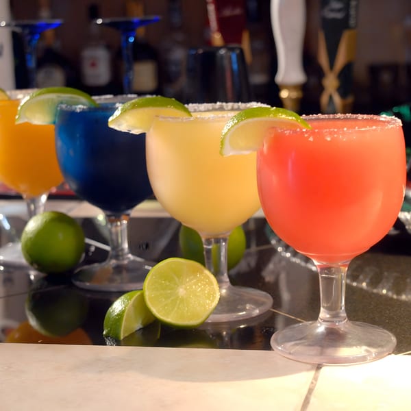 Four colorful margaritas with lime wedges and salted rims on a bar counter at El Molino.