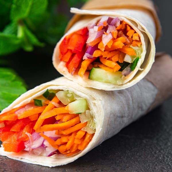Two vibrant El Molino Mexican wraps filled with shredded carrots, red peppers, and onions.